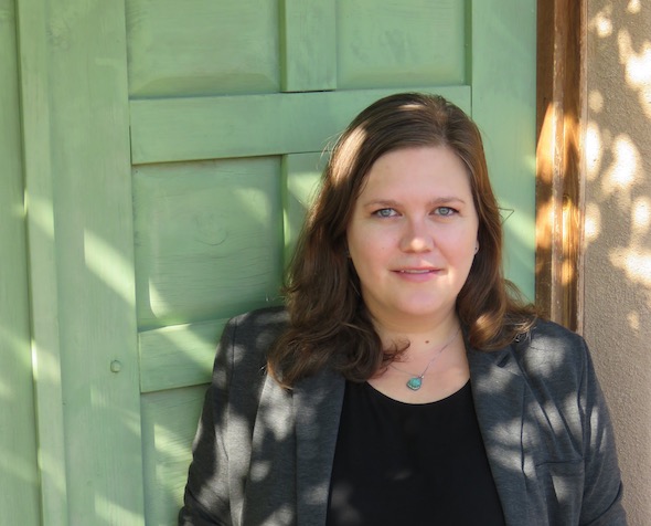 woman standing in sunlight in front of a green door