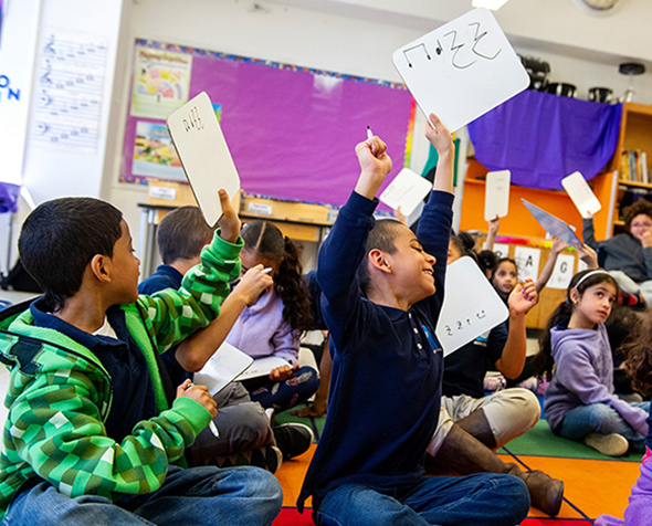 Kids holding up whiteboards with music notes on them