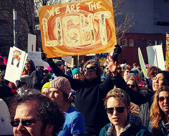Jami Duffy holds a protest sign that reads "We are the light"