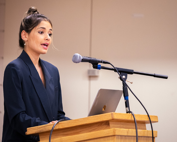 Sophia Kianni stands behind a podium speaking into a microphone