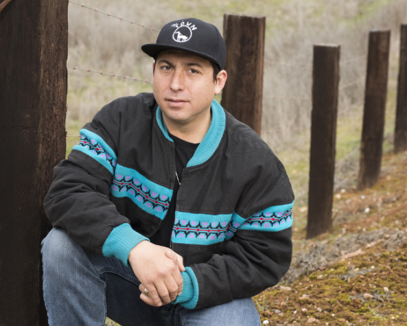 Photo of Tommy Orange outside beside a fence