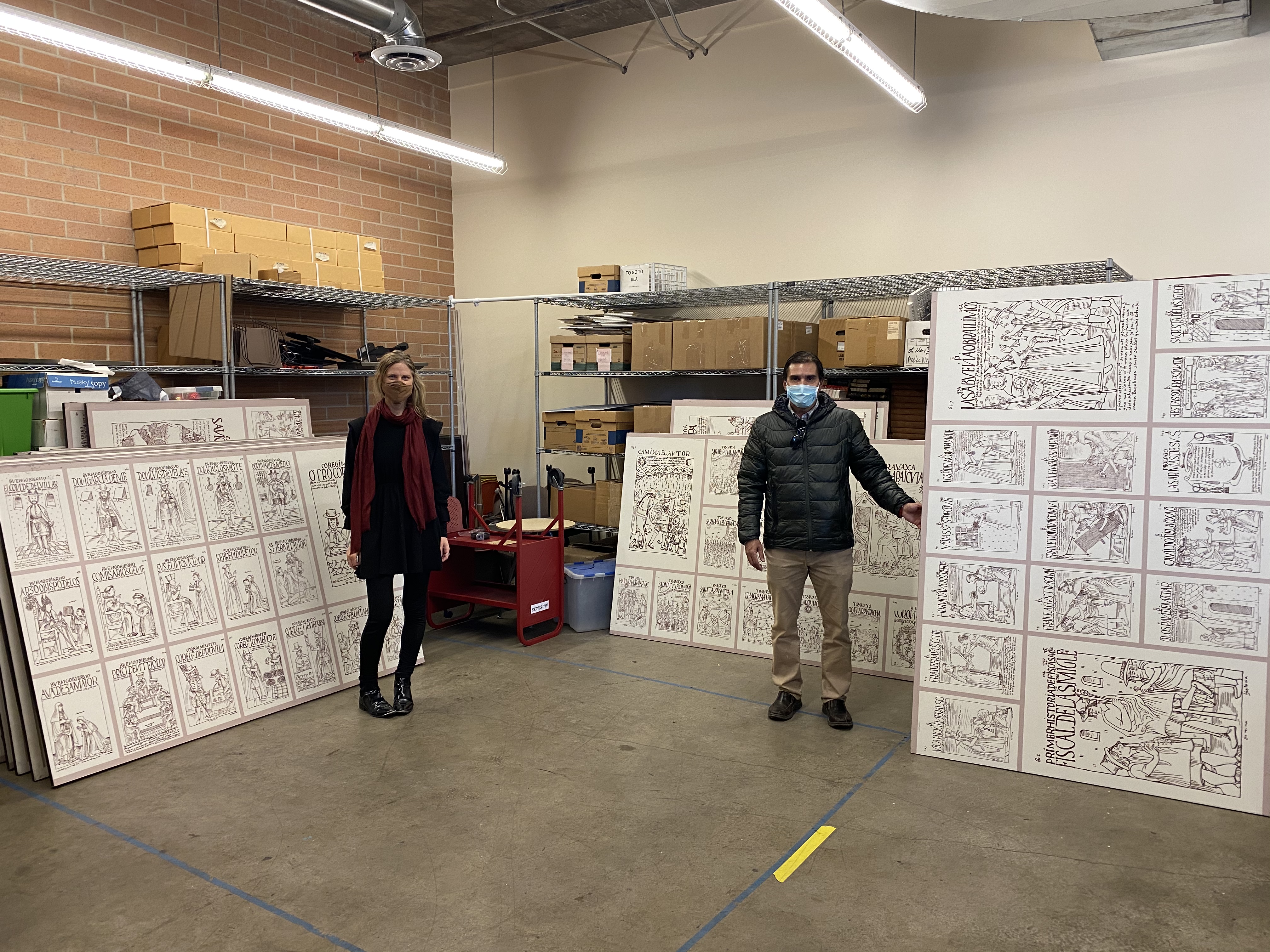 Two people stand with Guaman Poma panels on DU's campus