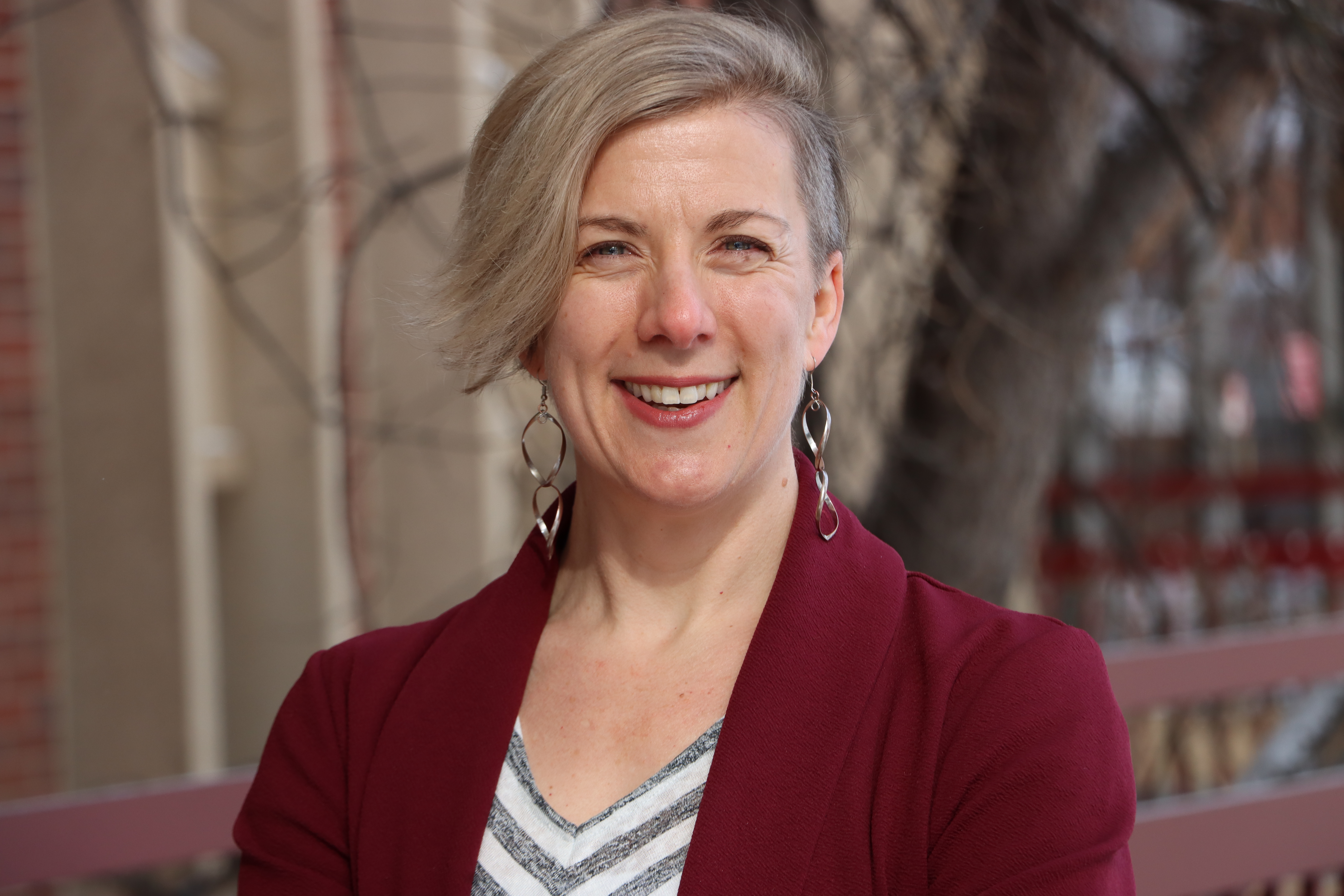 A woman smiles at the camera outside.