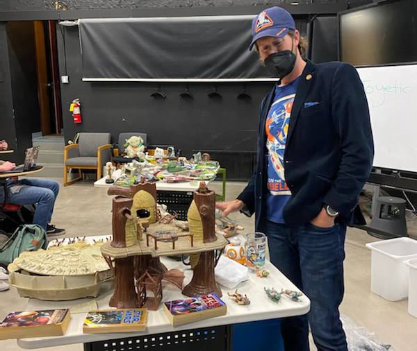 Andrew Matranga stands near a table of Star Wars memorabilia 