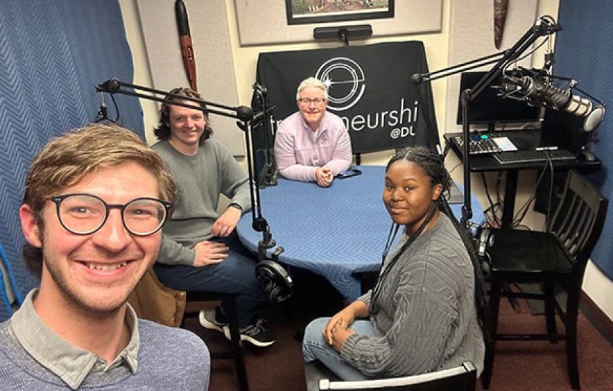 A professor and three DU students (now alumni) sit in a recording studio.