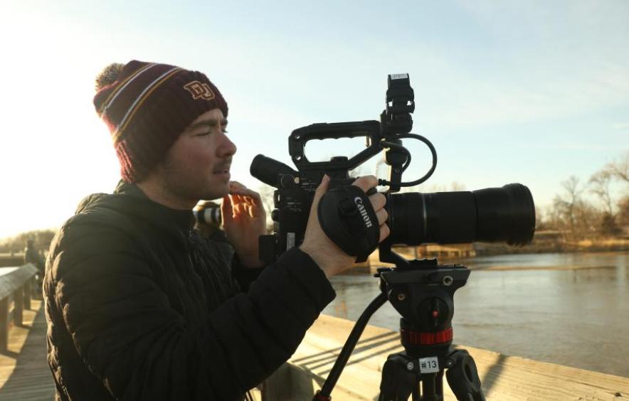 An undergraduate student in MFJS using a video camera to film a project for class.