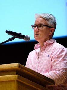 Professor Sheila Shroeder speaks into a microphone at a podium.