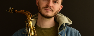 Professor Remy LeBoeuf holds a saxophone.