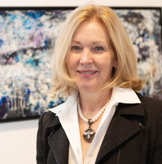 Patricia Aaron stands in front of a painting.
