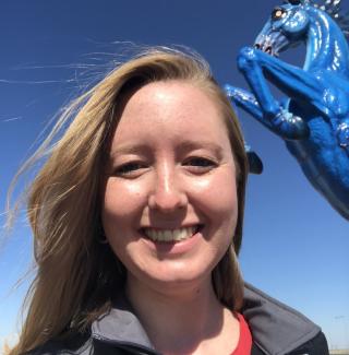 Emily Williams stands in front of the blue stallion statue at the entrance of Denver International Airport