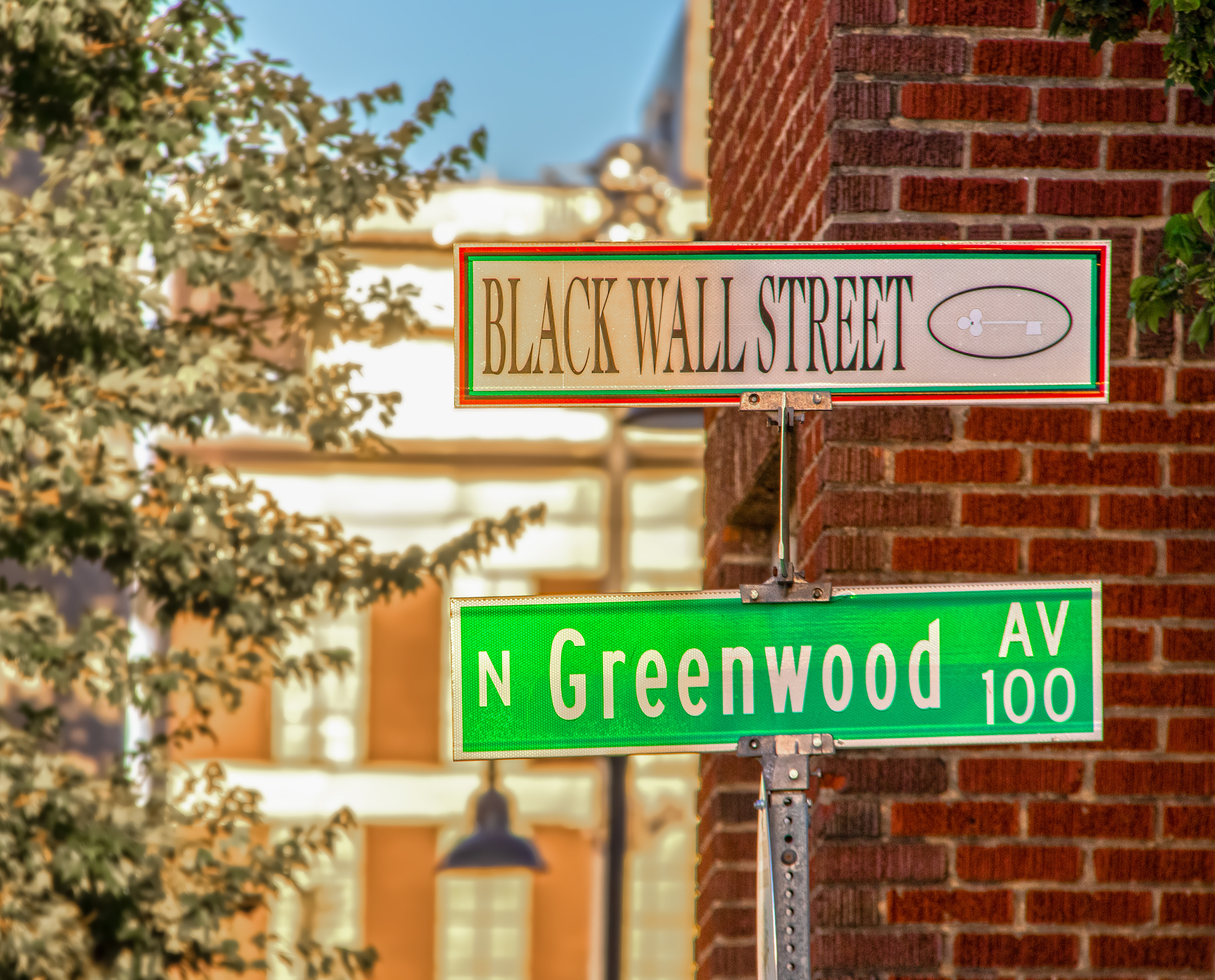 Two street signs, one that reads Black Wall Street, and the other that reads Greenwood.